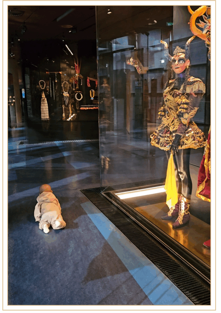 Bébé observant les costumes exposés au musée du Quai Branly à Paris pendant la visite contée Le voyage de Petit Ours